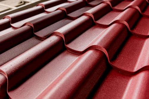 Red metallic roof tiles background with drops of water.